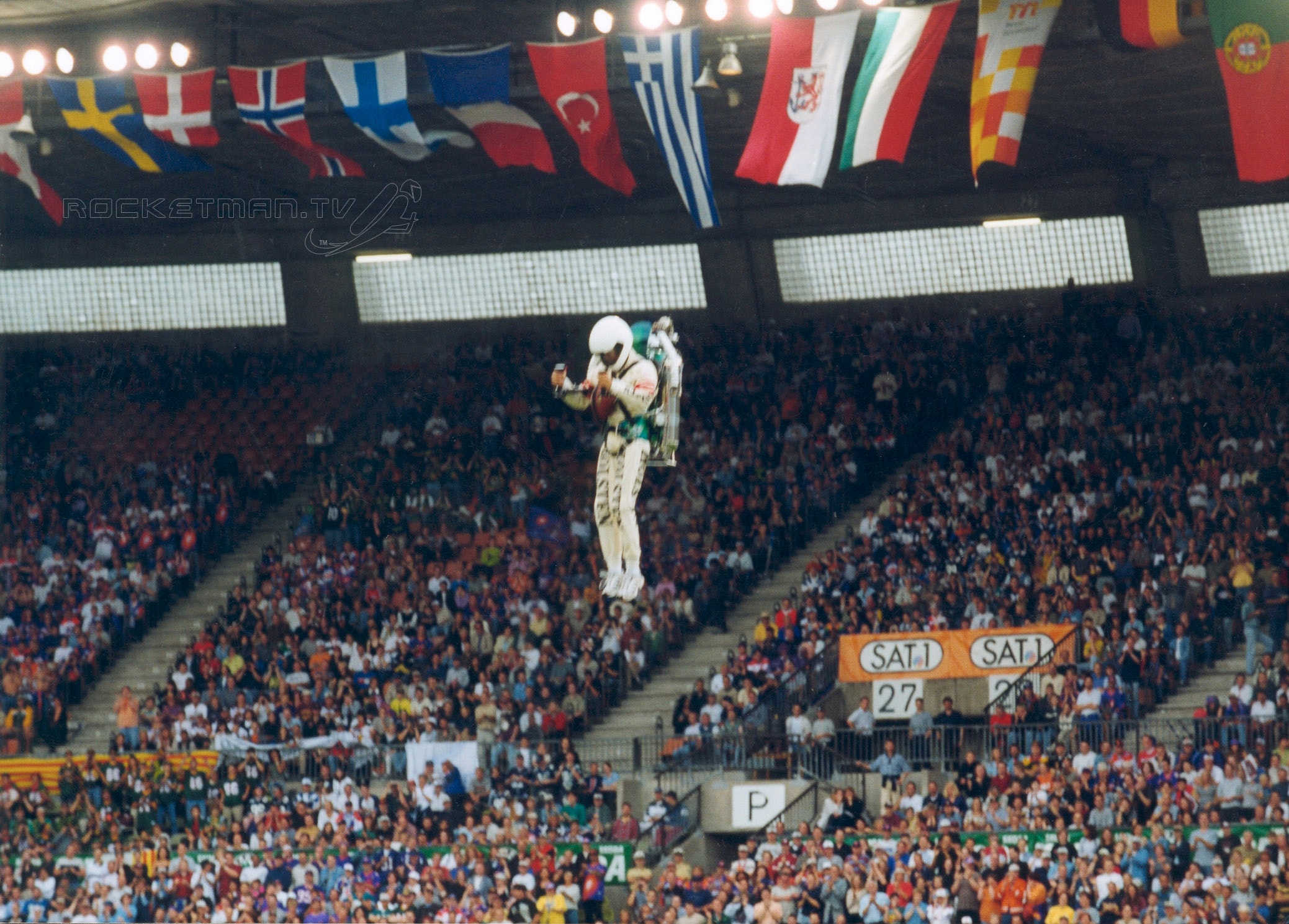 The Rocketman flying over a packed international stadium with world flags
