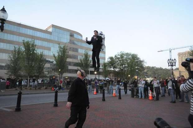 The Rocketman flying over an urban plaza crowd without a helmet