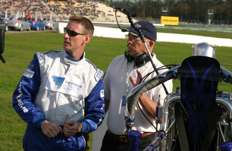 The Rocketman in a pre-flight safety briefing with a crew member at a motorsport event